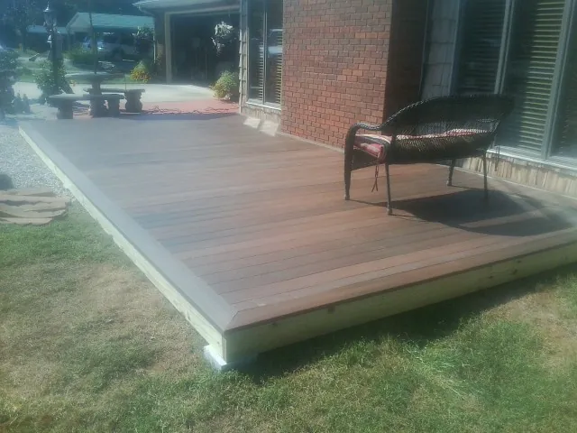 New wood deck and wicker chair beside a brick house in Dalton