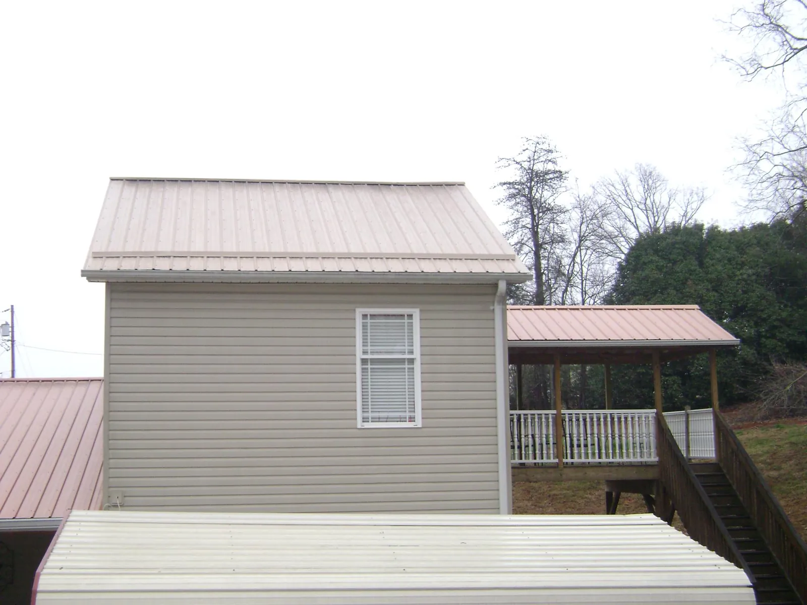 Tan metal roofs on a two story addition and attached porch, from a Roof Replacement job in Dalton